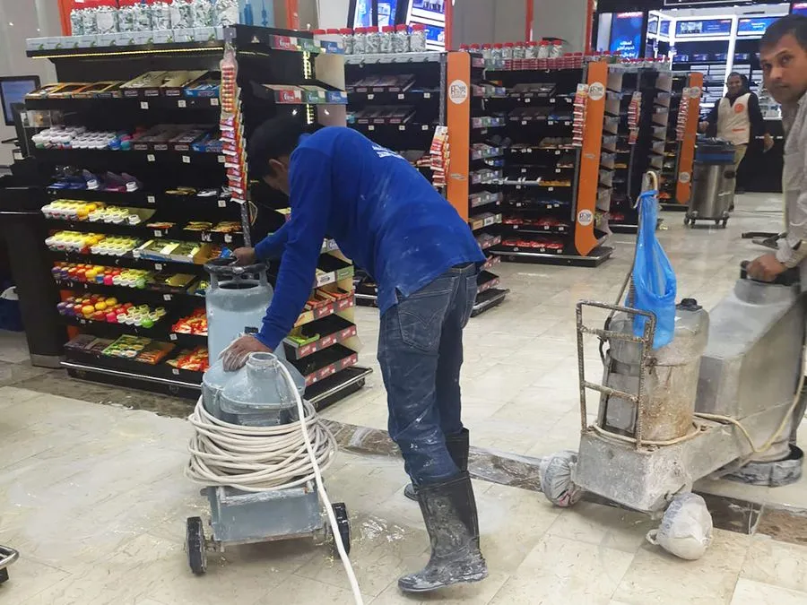 A men cleaning floor of a commercial building - wearing blue shirt