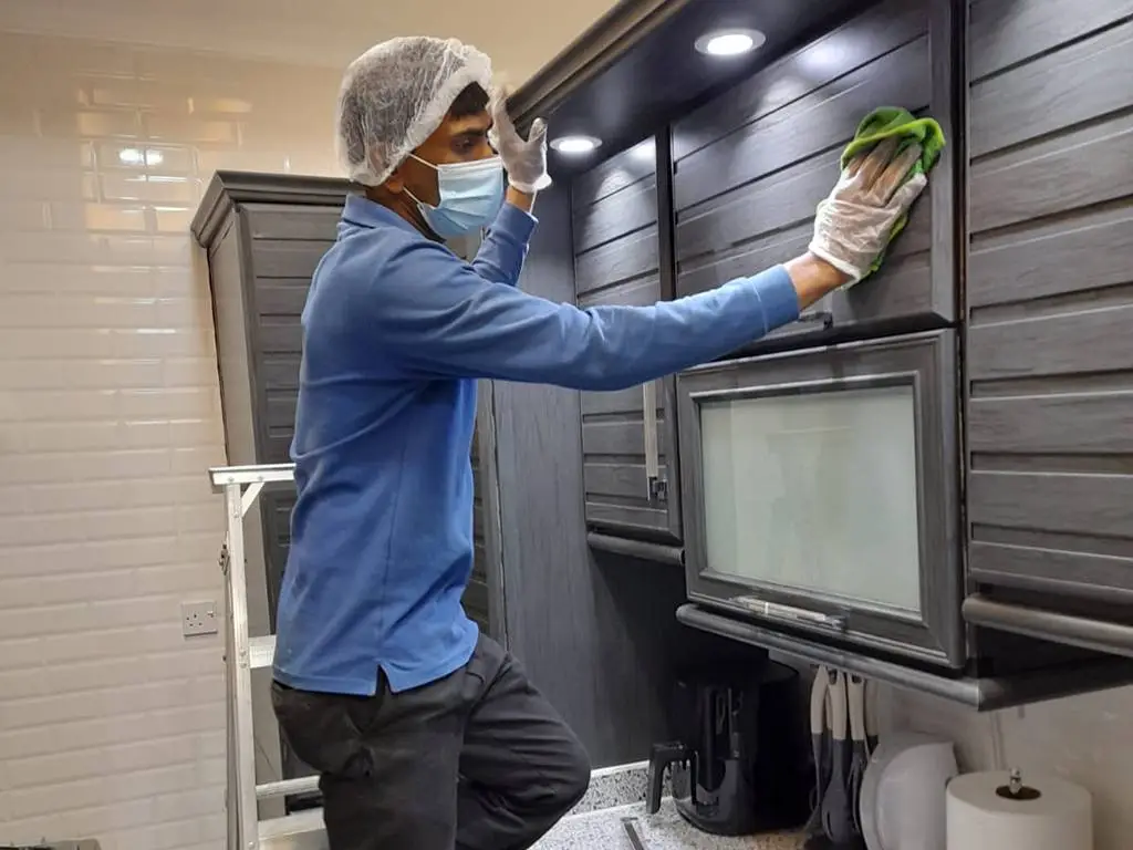 A man cleaning house - Professional House Cleaner, wearing blue shirt, white gloves, black pant