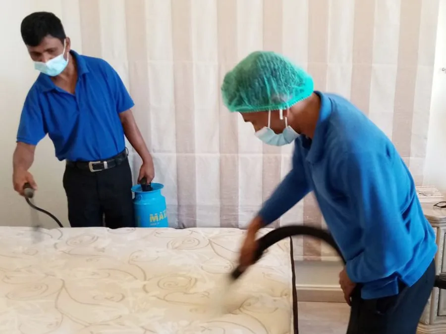 Two Professional Pest control cleaner working with spray machine, wearing blue shirt and head cover